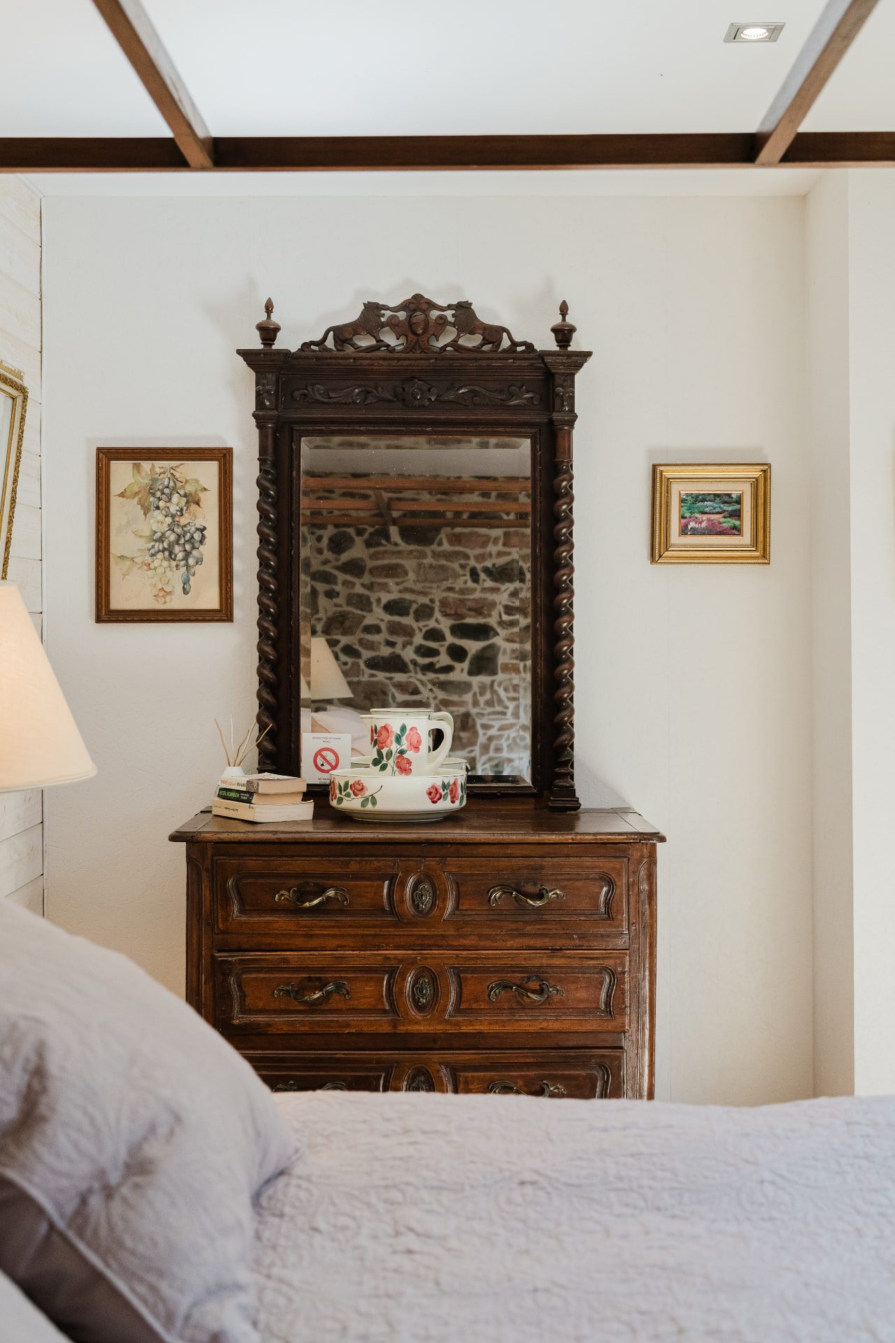 Commode ancienne et miroir en bois sculpté face au lit de la Chambre Confort