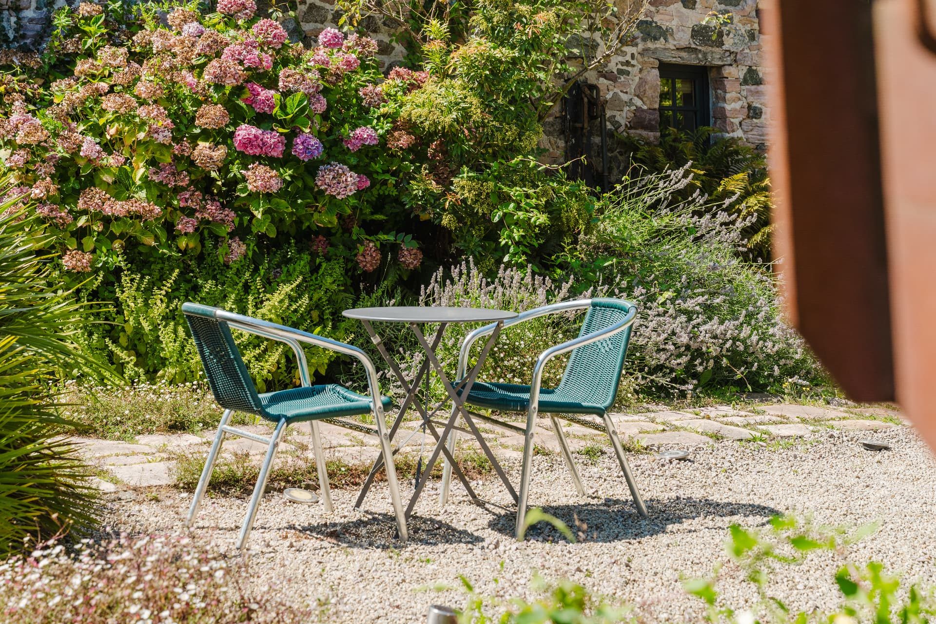 Table et chaises de jardin devant les hortensias en fleurs