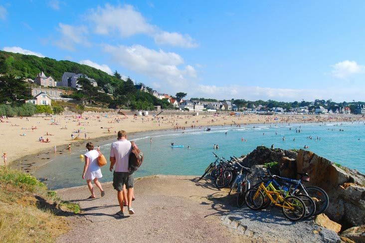 La plage de Caroual à Erquy, promeneurs et vélos au bord de l'eau